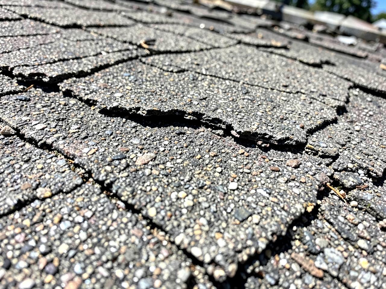 Close-up of cracked, weathered asphalt shingles